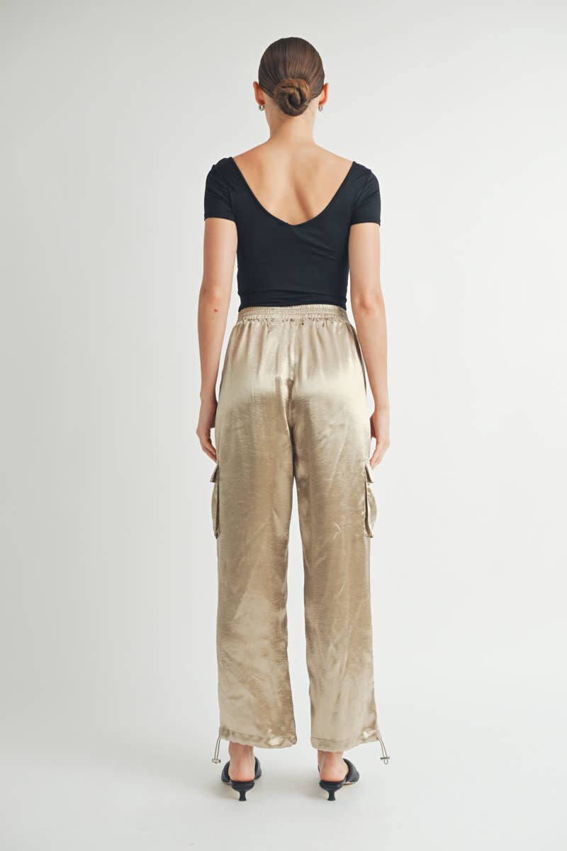 Back of Gold Satin Cargo Pants with Adjustable Drawstring Hem where its open on bottom with heels 