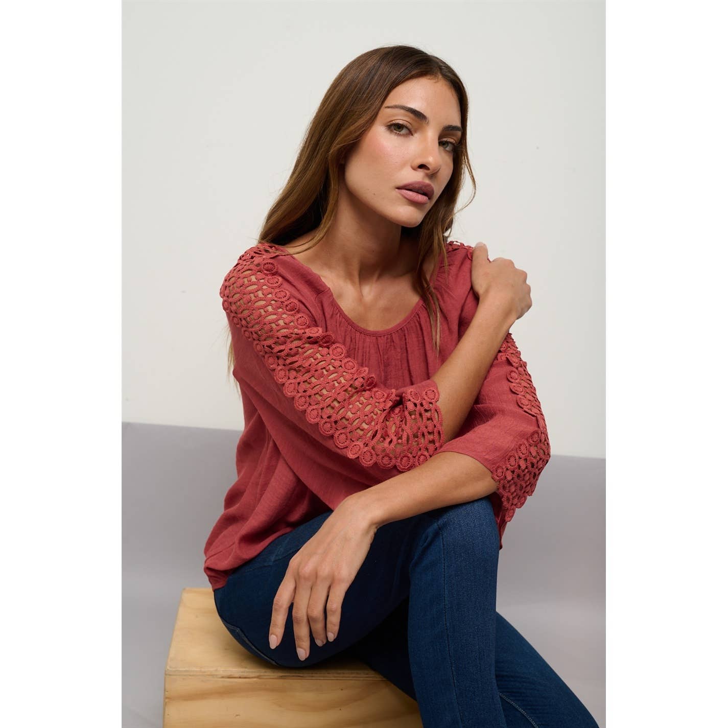 Brick red peasant top with a scoop neckline, three-quarter crochet sleeves, and a bubble hem.